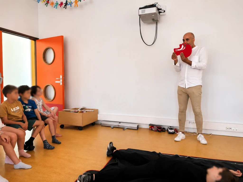 Le formateur de La Brigade du Cœur explique aux enfants de l'ALSH de Pleyben comment libérer les voies aériennes d'une victime inconsciente.