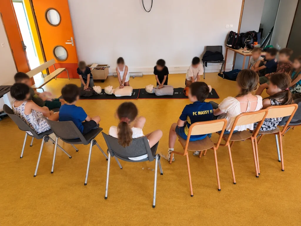 Des enfants de l'ALSH de Pleyben réalisent leurs premiers massages cardiaques sur des mannequins lors d'un atelier animé par La Brigade du Cœur.