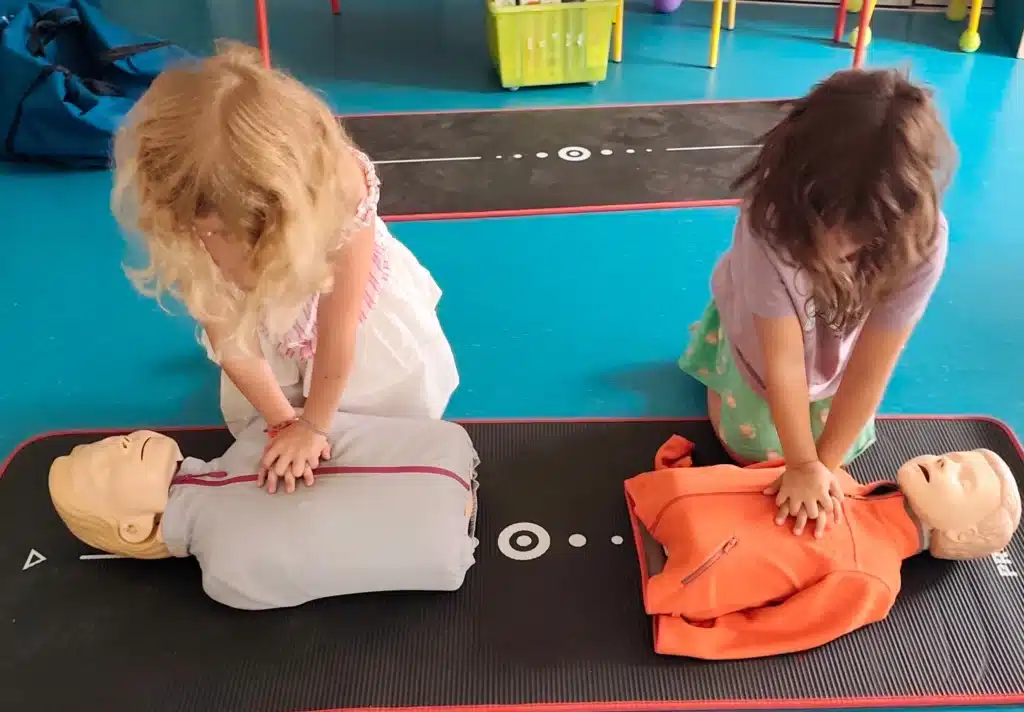 Des enfants apprennent le massage cardiaque sur des mannequins pédagogiques pendant une intervention premiers secours à l'école
