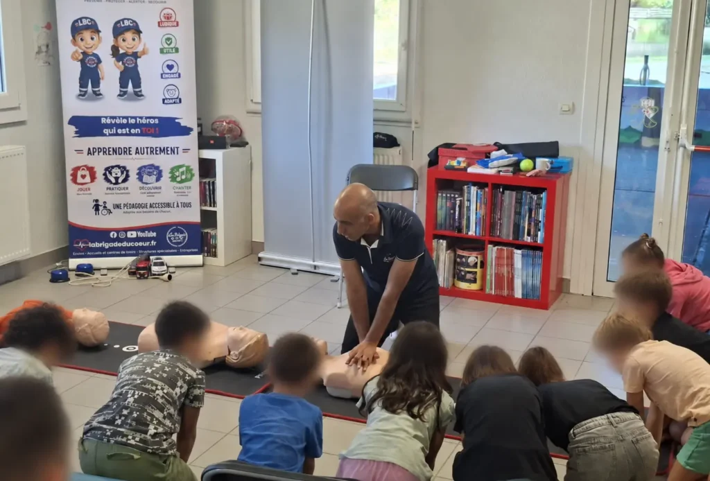 Démonstration du massage cardiaque devant des enfants lors d’un atelier de premiers secours à Chantepie.